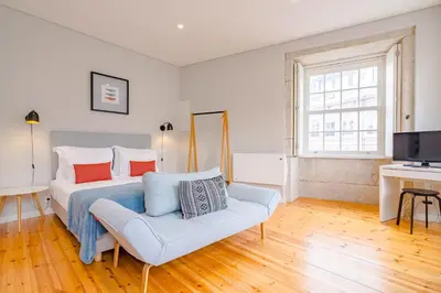 a bedroom with a bed and a couch and a television at YOUROPO - City Center Ribeira Porto in Porto