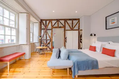 a bedroom with a large bed and a chair at YOUROPO - City Center Ribeira Porto in Porto