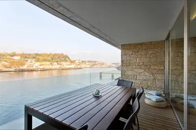a room with a table and a view of the water at HS Cais Cavaco in Vila Nova de Gaia