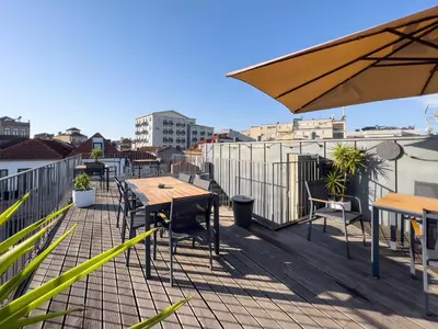 a deck with tables and chairs and an umbrella at Galerias Nightlife Fashion Flats in Porto