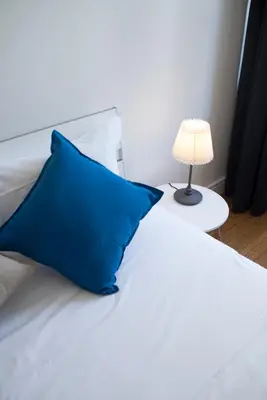 a bed with a blue pillow and a lamp on a table at Sleep in Centre in Porto