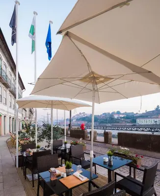 a patio with tables and a large white umbrella at Vila Gale Porto Ribeira in Porto