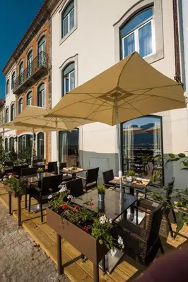 a patio with tables and umbrellas in front of a building at Vila Gale Porto Ribeira in Porto