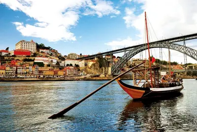 a boat in the water in front of a bridge at Vila Gale Porto Ribeira in Porto