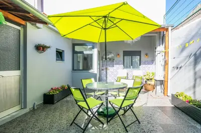 a table and chairs with a yellow umbrella on a patio at Apartamento Garden Avenue in Porto