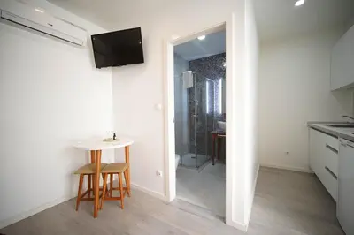 a kitchen with a small table and a television on the wall at The Blue and White Porto House in Porto