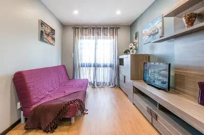 a living room with a purple couch and a tv at GuestReady - Sound of Nature - T1 Boavista in Porto