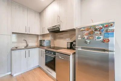 a kitchen with white cabinets and a stainless steel refrigerator at GuestReady - Sound of Nature - T1 Boavista in Porto