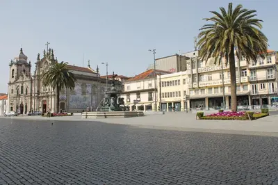 a city square with a fountain and palm trees and buildings at Pensão França in Porto