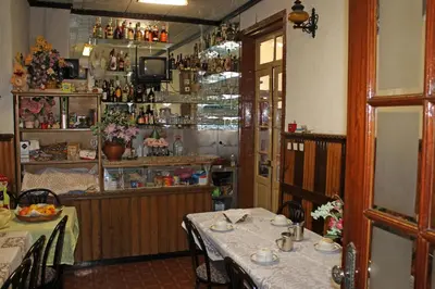 a dining room with a table and chairs and a kitchen at Pensão França in Porto