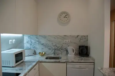a kitchen with a microwave and a clock on the wall at OportoView Alegria Apartment in Porto