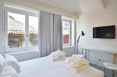 a white bedroom with a bed and a window at House of Artists in Porto