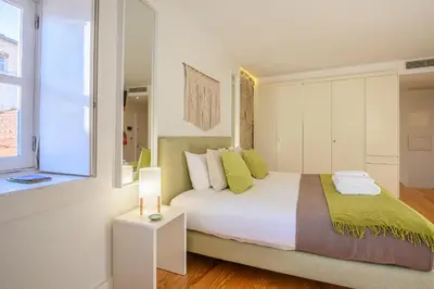 a white bedroom with a bed and a window at PWHC Miragaia Apartments in Porto