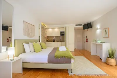 a bedroom with a bed and a kitchen at PWHC Miragaia Apartments in Porto