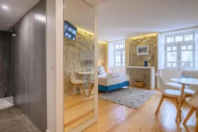 a bedroom and a living room with a bed and a table at PWHC Miragaia Apartments in Porto