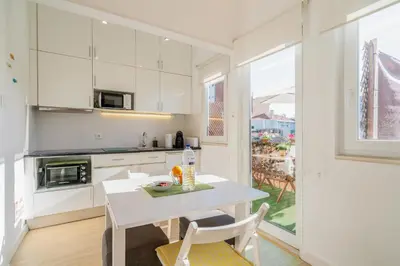 a white kitchen with a white table and chairs at Covelo Park Apartment in Porto