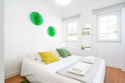 a white bedroom with a white bed with yellow and green pillows at Covelo Park Apartment in Porto