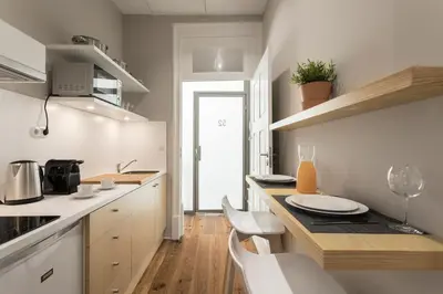 a kitchen with white cabinets and a table and chairs at Ribeira Historic Apartments in Porto