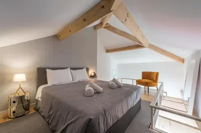 a bedroom with a large bed and a chair at Sá de Noronha Mezzanine w Terrace in Porto