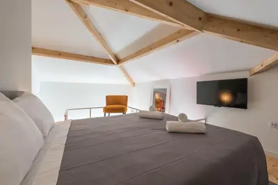 a bedroom with a large bed with a tv on the wall at Sá de Noronha Mezzanine w Terrace in Porto