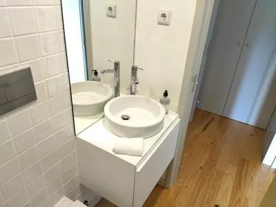 a white bathroom with a sink and a mirror at Lusitania Garden Apartment - Jardim Privado in Porto