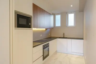a kitchen with white cabinets and a microwave at N Apartments - Bolhão in Porto