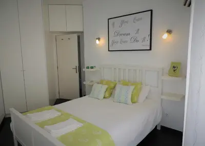 a small bedroom with a white bed with green pillows at Rendez Vous Porto in Porto