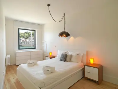 a bedroom with a large white bed with two lights on it at FLH Luxury Porto River View in Vila Nova de Gaia