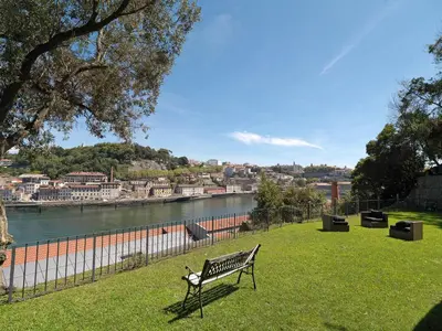 a park bench sitting on the grass next to a river at FLH Luxury Porto River View in Vila Nova de Gaia