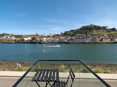 a bench sitting next to a body of water at FLH Luxury Porto River View in Vila Nova de Gaia