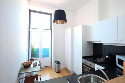 a kitchen with white cabinets and a large window at Porto Duke's House in Porto