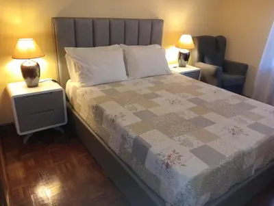 a bedroom with a bed with two lamps and a chair at Apartamento Alvares Cabral in Vila Nova de Gaia