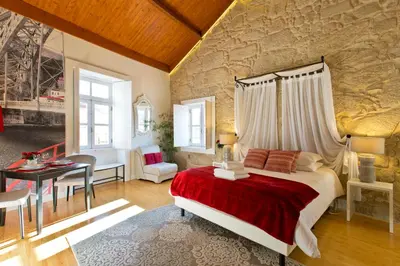 a bedroom with a bed and a stone wall at Ribeira Stay Apartments in Porto