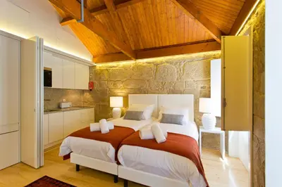 a bedroom with a large bed and a stone wall at Ribeira Stay Apartments in Porto