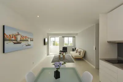 a white living room with a table and a kitchen at Downtown Prime Porto in Porto