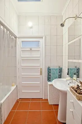 a bathroom with a white door and a tub and a sink at Camarao Apartment in Porto