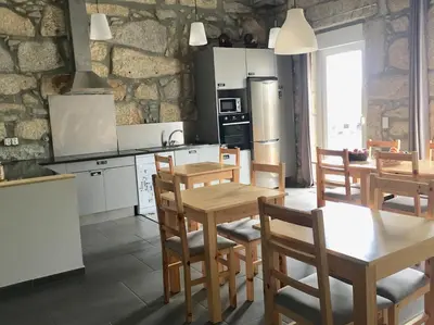 a kitchen with wooden tables and chairs and a stone wall at Campanhã Boutique Station in Porto