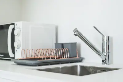 a white kitchen with white cabinets and a microwave at GuestReady - Gemini Apartment in Porto