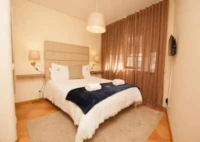 a bedroom with a bed with two towels on it at ML Formosa Deluxe Rooms in Porto