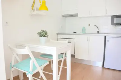 a white kitchen with a white table and chairs at Porto Garden Villas | Downtown in Vila Nova de Gaia