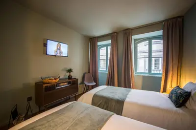 a hotel room with two beds and a television at Laurear Guest House in Porto