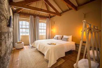 a bedroom with a white bed and a large window at Laurear Guest House in Porto