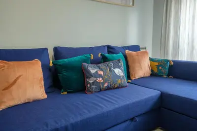 a blue couch with colorful pillows on it at GuestReady - Back to Little World in Porto