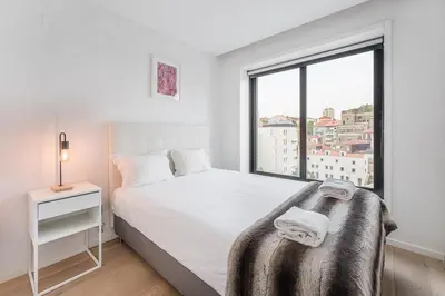 a white bedroom with a bed and a window at GuestReady - Cosy spot near Porto city centre in Porto