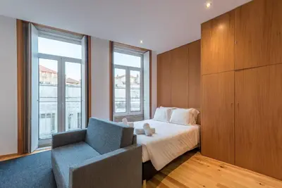 a bedroom with a bed and a chair and window at GuestReady - Given to fly in Porto