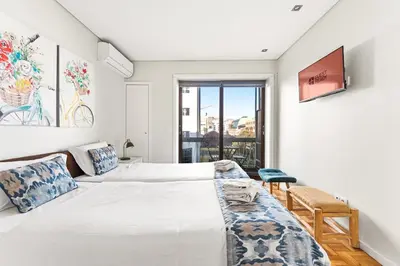 a white bedroom with two beds and a blue chair at GuestReady - Jupiter's Moon in Porto
