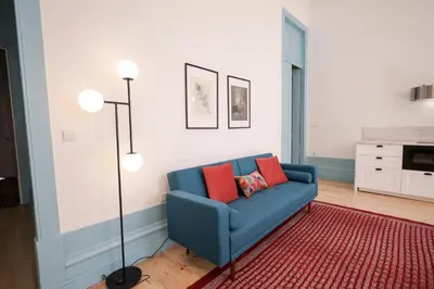 a living room with a blue couch and a floor lamp at Adorable Apartments in Great Area in Porto