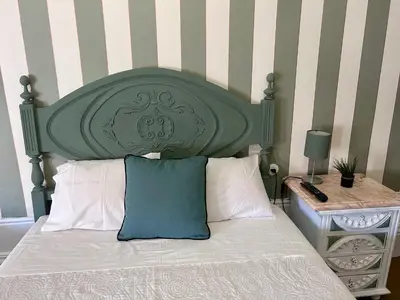 a bed with a green headboard and white pillows at Monte Sinai Guest House in Porto
