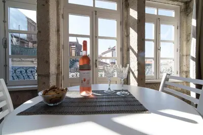 a bottle of wine on a white table with windows at Casas do Loureiro in Porto