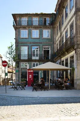 a building with tables and an umbrella in front of it at Oporto Blue Picaria - Unique Citycenter Apartment in Porto